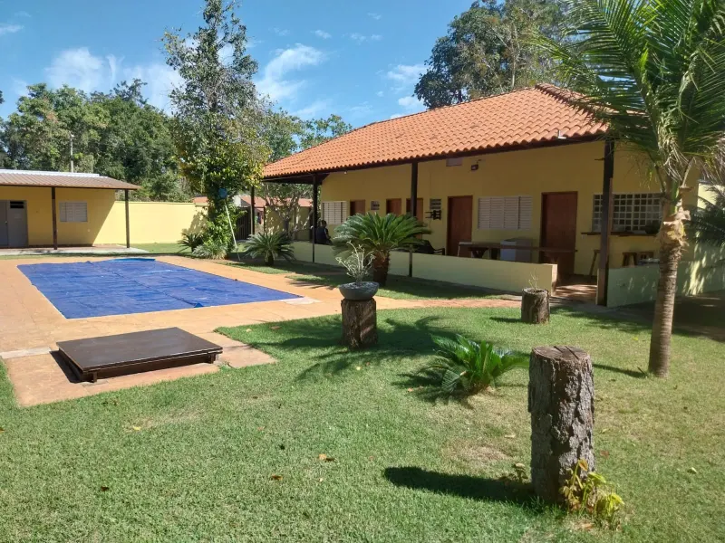 Área comum da casa principal com mesa, TV e cozinha