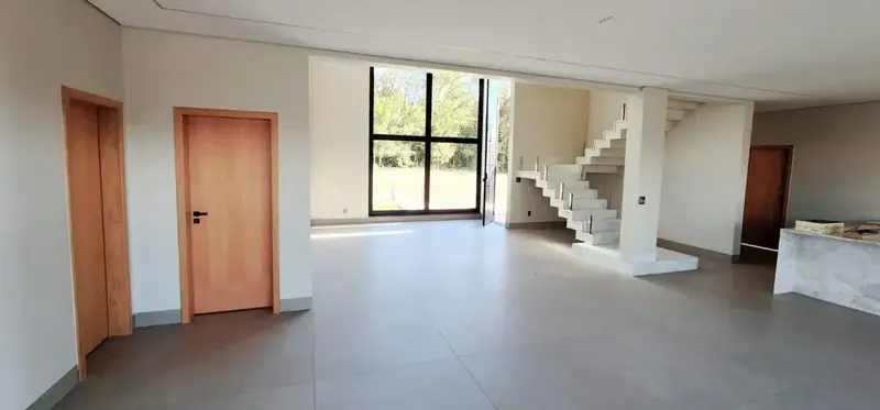 Living com pé-direito duplo e escada do sobrado no Jardins França, Goiânia